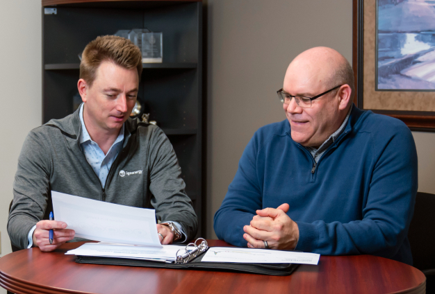 A man wearing an IGS shirt going over options with a business person while sitting at a table