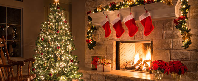 Decorated Christmas tree next to a fireplace and decorated mantel)