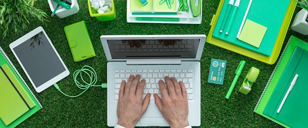 Laptop, tablet, notebooks and desk material outside on grass